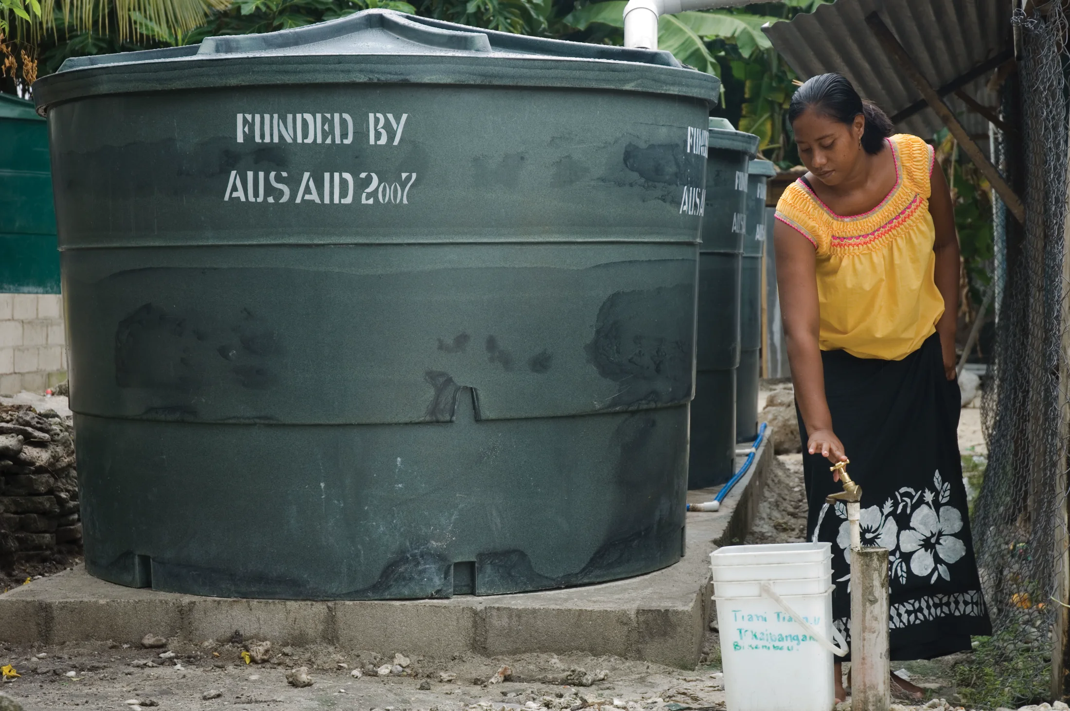 Maria Kaburoro collects freshwater from a rainwater tank in Kiribati